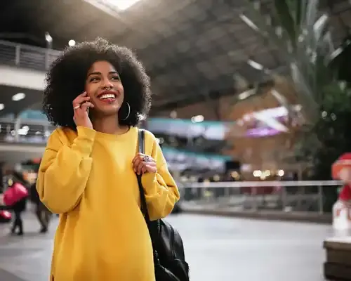 seguro-de-viaje-para-una-mujer-afro-hermosa-que-utiliza-el-móvil-en-la-estación-de-tren